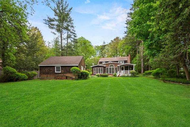 back of property with a sunroom, a lawn, and a chimney