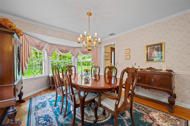 dining room featuring a chandelier, wallpapered walls, wood finished floors, baseboards, and ornamental molding