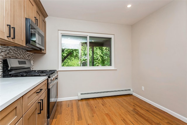 kitchen with appliances with stainless steel finishes, a baseboard radiator, baseboards, tasteful backsplash, and recessed lighting