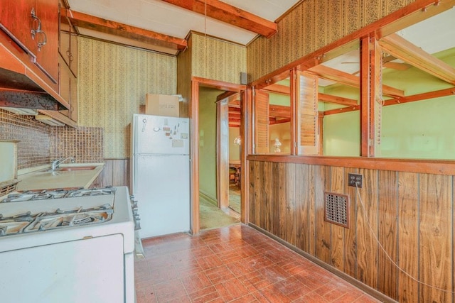 62-12 60th Dr, Maspeth, NY 11378 - kitchen featuring wallpapered walls, white appliances, brick patterned flooring, a sink, and beam ceiling