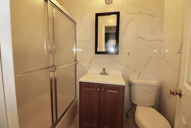 full bathroom with vanity, a shower with shower door, toilet, and tile walls