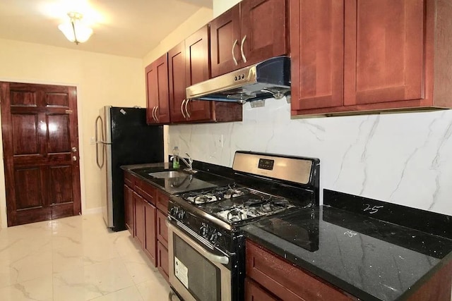 kitchen with stainless steel gas range oven, under cabinet range hood, a sink, light marble finish floors, and tasteful backsplash