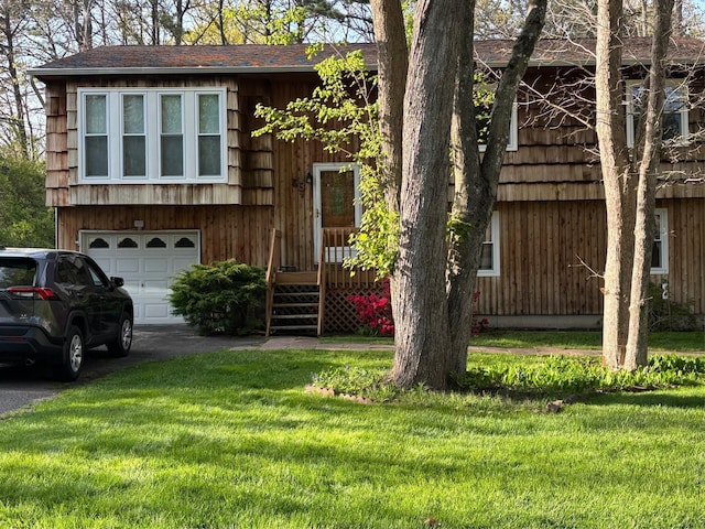 view of front of home featuring asphalt driveway, an attached garage, and a front lawn