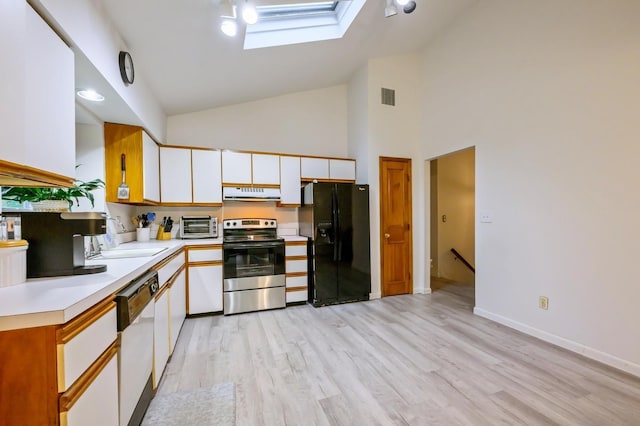 kitchen featuring stainless steel electric range, black fridge, a sink, a skylight, and range hood