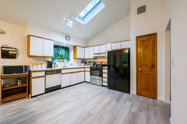 kitchen featuring black fridge, dishwasher, stainless steel microwave, range with electric stovetop, and a skylight