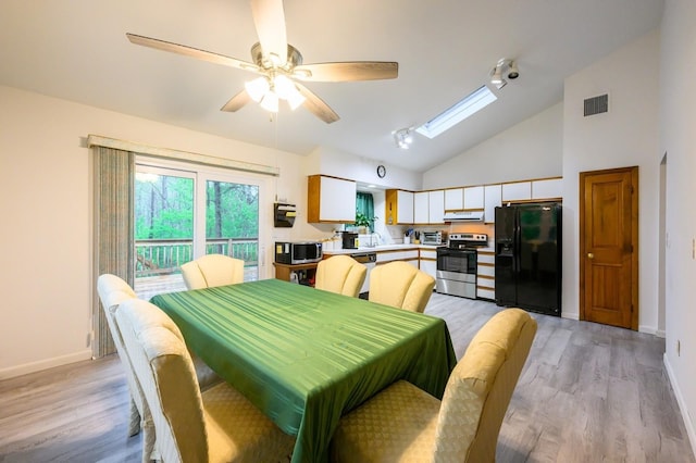 dining area with light wood-style floors, a skylight, baseboards, ceiling fan, and high vaulted ceiling