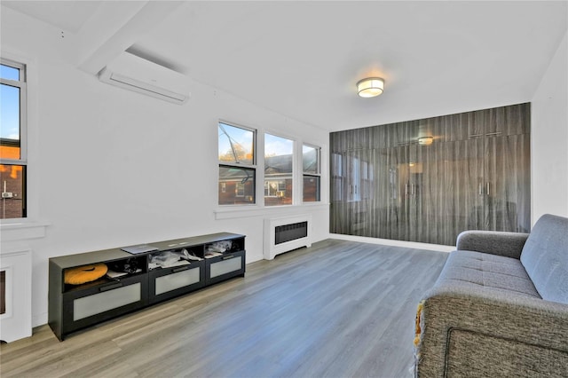 living room with a wall mounted air conditioner, wood finished floors, a fireplace, and heating unit