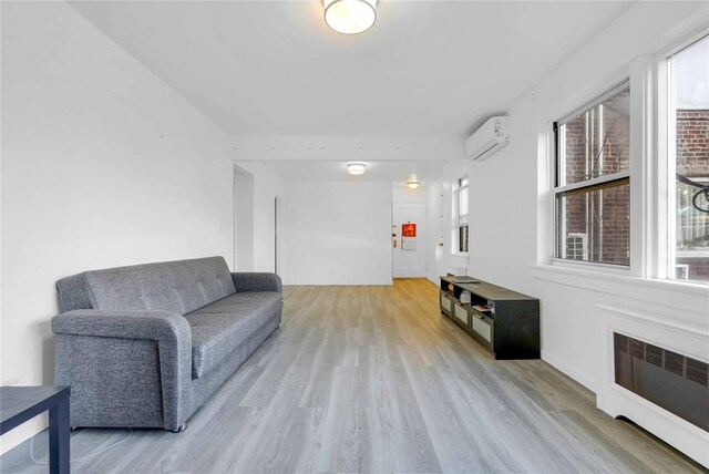 living area with radiator, light wood-type flooring, an AC wall unit, and baseboards