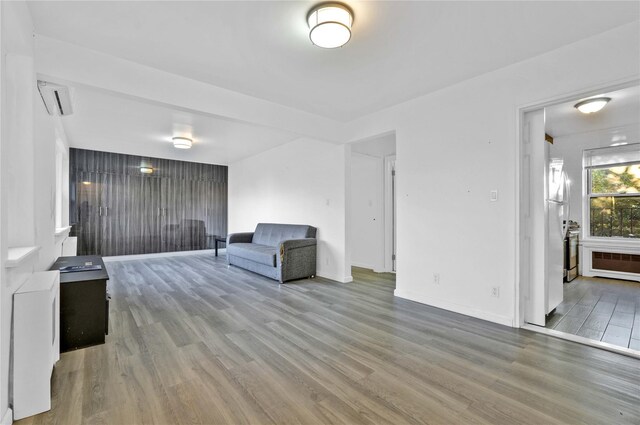 living area featuring wood finished floors, baseboards, and radiator