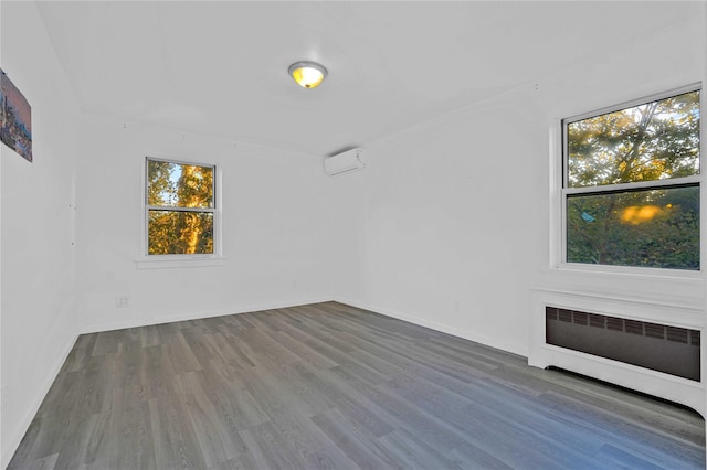 unfurnished room with radiator heating unit, wood finished floors, and healthy amount of natural light