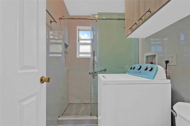 clothes washing area with washer / clothes dryer and cabinet space