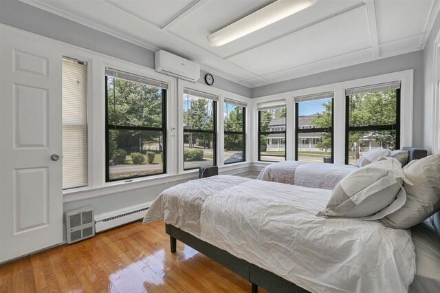 541 Broadway, Monticello, NY 12701 - bedroom featuring a wall unit AC, a baseboard radiator, multiple windows, and wood finished floors