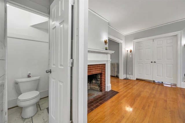 541 Broadway, Monticello, NY 12701 - bathroom featuring radiator heating unit, toilet, a fireplace, baseboards, and crown molding