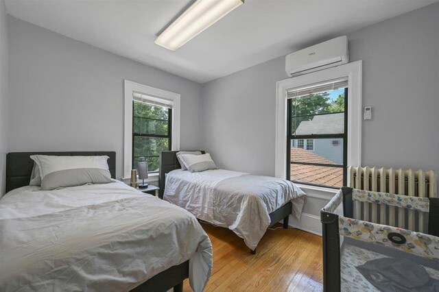 541 Broadway, Monticello, NY 12701 - bedroom with an AC wall unit, multiple windows, light wood finished floors, and radiator