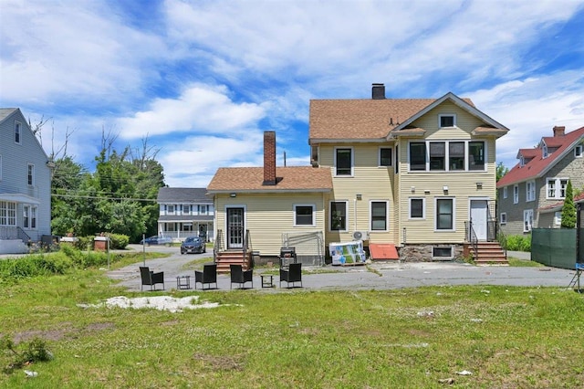 541 Broadway, Monticello, NY 12701 - rear view of property featuring entry steps, a chimney, a lawn, and a patio