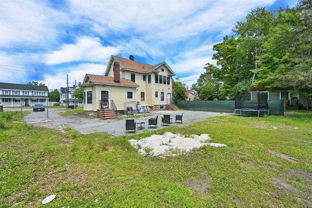 541 Broadway, Monticello, NY 12701 - back of house featuring a trampoline, a yard, a patio area, and a chimney