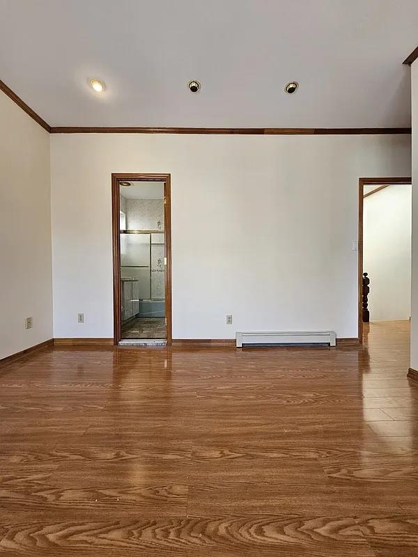 unfurnished room featuring crown molding, wood finished floors, baseboards, a baseboard radiator, and recessed lighting