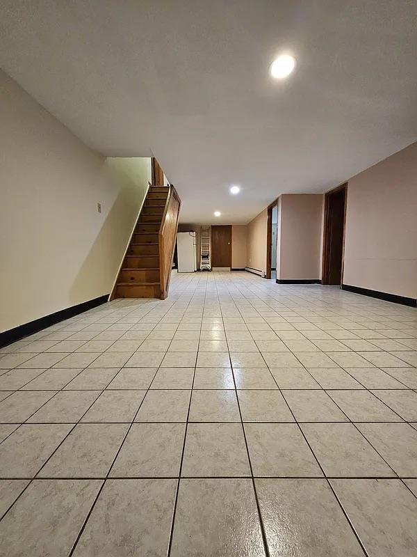 below grade area featuring stairs, baseboards, recessed lighting, and light tile patterned flooring