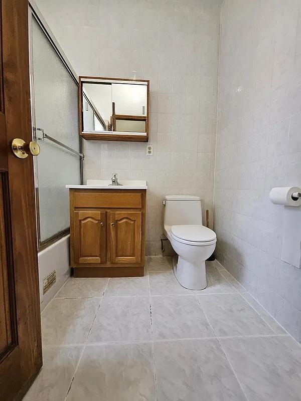 bathroom with toilet, vanity, enclosed tub / shower combo, and tile patterned floors