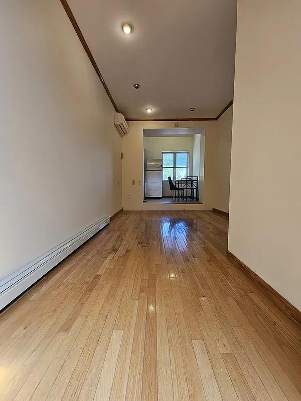 unfurnished room featuring crown molding, a baseboard radiator, light wood-style floors, baseboards, and recessed lighting