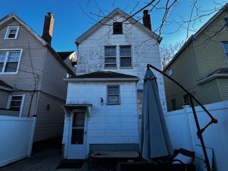 rear view of house with a chimney and fence