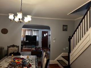 dining space with arched walkways, ornamental molding, a chandelier, stairway, and baseboards