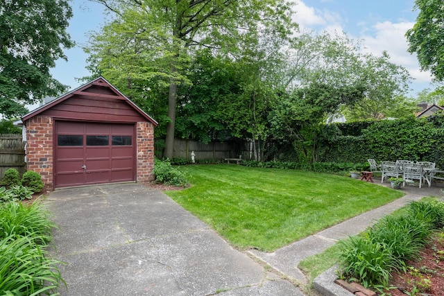 view of yard featuring concrete driveway, a garage, and an outbuilding