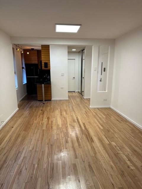 unfurnished living room with wood finished floors and baseboards