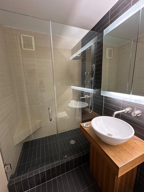 bathroom featuring tile walls, a shower stall, vanity, tile patterned flooring, and backsplash