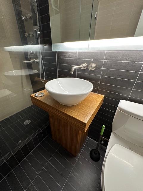 full bathroom featuring tile walls, tile patterned flooring, toilet, and tiled shower