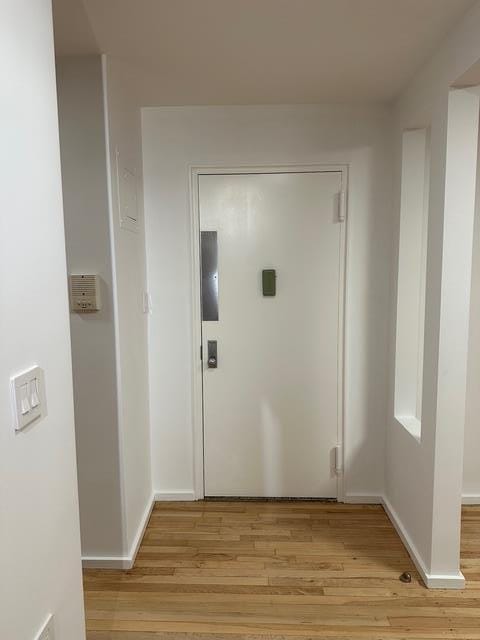 hall with light wood finished floors and baseboards