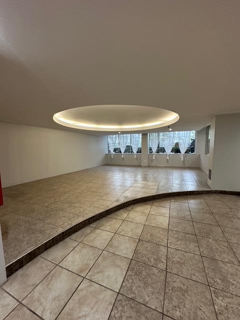 tiled empty room with a raised ceiling and inlaid floor details
