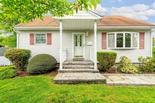 view of front facade with a front yard and roof with shingles