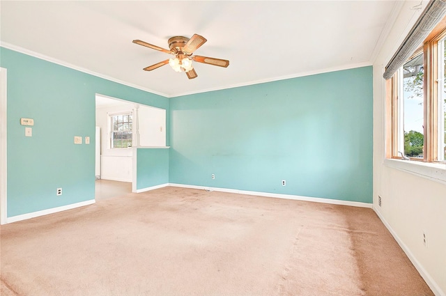 carpeted empty room featuring crown molding, baseboards, and ceiling fan