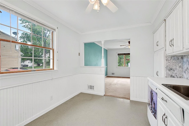 kitchen featuring ceiling fan, a wainscoted wall, white cabinets, light colored carpet, and light countertops