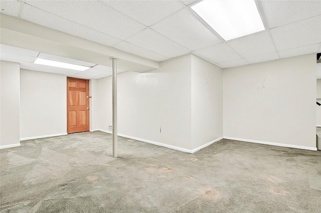 finished basement featuring a drop ceiling, carpet flooring, and baseboards