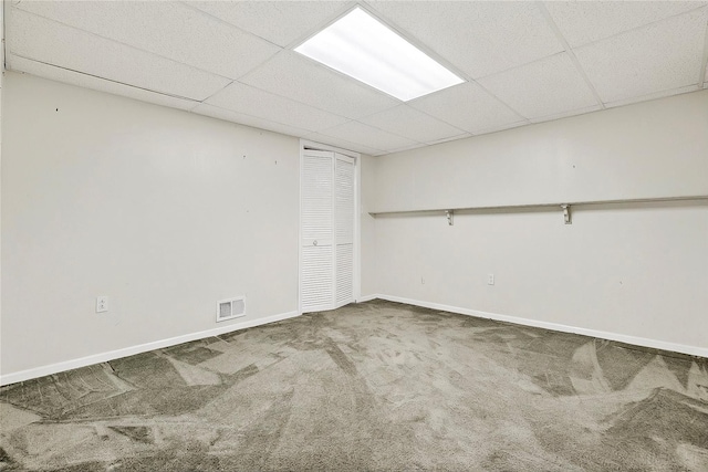 finished below grade area with a paneled ceiling, carpet, and baseboards