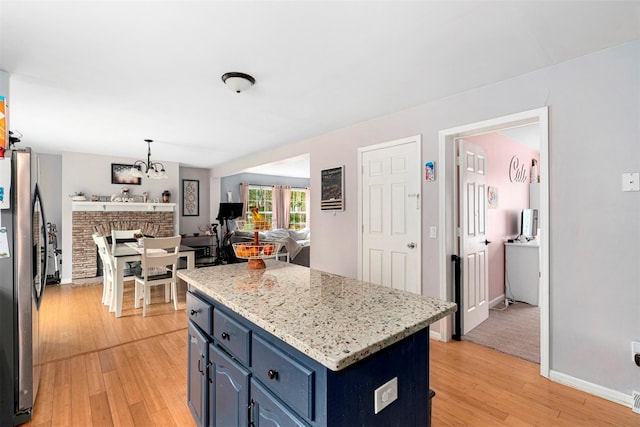 kitchen with freestanding refrigerator, light wood finished floors, blue cabinetry, and a center island