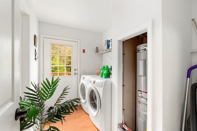 clothes washing area featuring electric water heater, washer and dryer, and light wood-style flooring