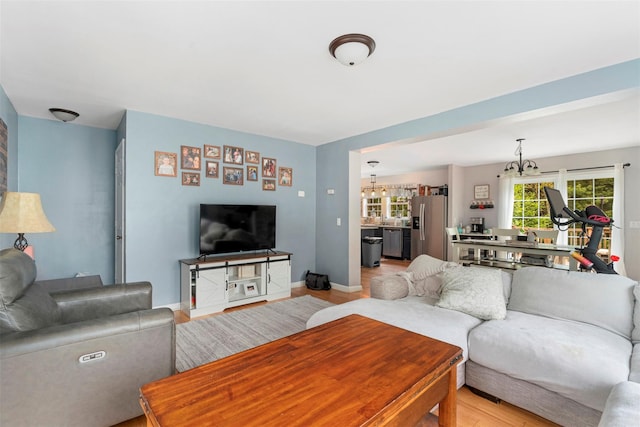 living area featuring a chandelier, light wood-style floors, and baseboards
