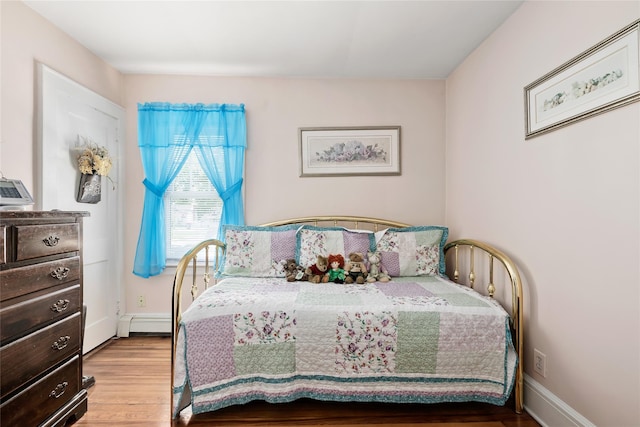 bedroom featuring a baseboard radiator and wood finished floors