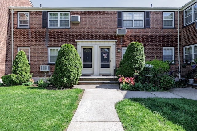 multi unit property featuring a front lawn, brick siding, and an AC wall unit