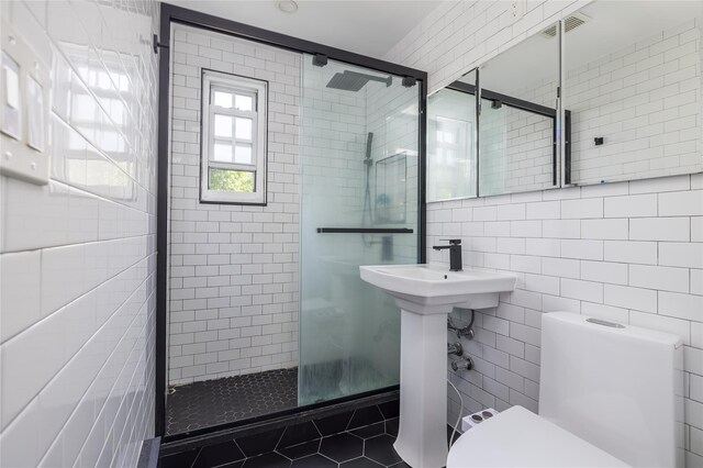 bathroom featuring tile walls, a stall shower, toilet, and tile patterned floors