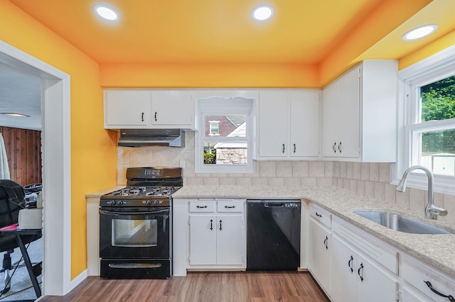 66 Elmwood Ave, Hempstead, NY 11550 - kitchen with black appliances, a sink, under cabinet range hood, wood finished floors, and backsplash
