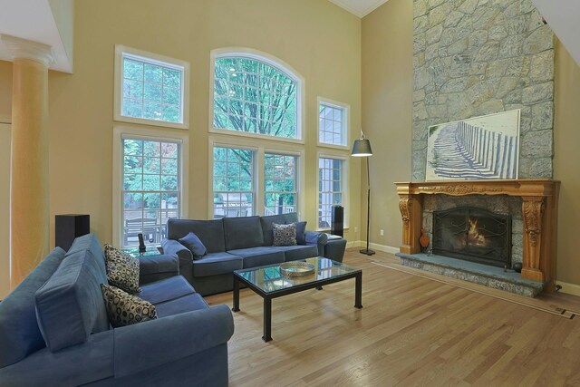 1988 Beekman Ct, Yorktown Heights, NY 10598 - living room with a stone fireplace, a high ceiling, light wood-type flooring, ornamental molding, and baseboards