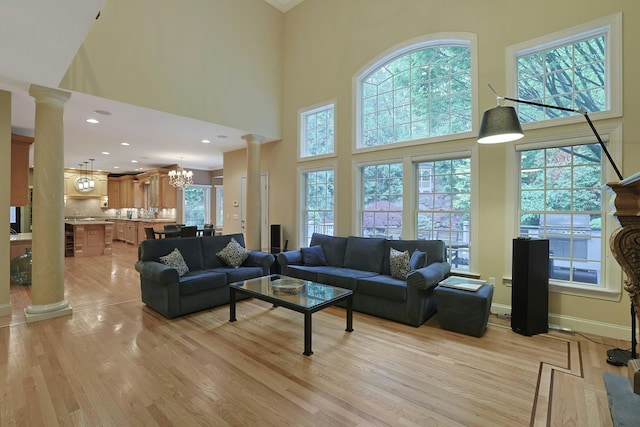 1988 Beekman Ct, Yorktown Heights, NY 10598 - living area featuring ornate columns, healthy amount of natural light, a towering ceiling, light wood-style flooring, and a chandelier