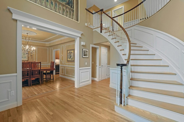 1988 Beekman Ct, Yorktown Heights, NY 10598 - stairway with a decorative wall, a chandelier, crown molding, a high ceiling, and wood finished floors