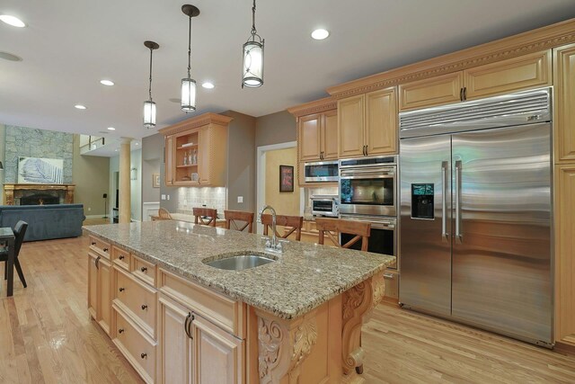 1988 Beekman Ct, Yorktown Heights, NY 10598 - kitchen with built in appliances, a sink, a center island with sink, light wood-style flooring, and a fireplace