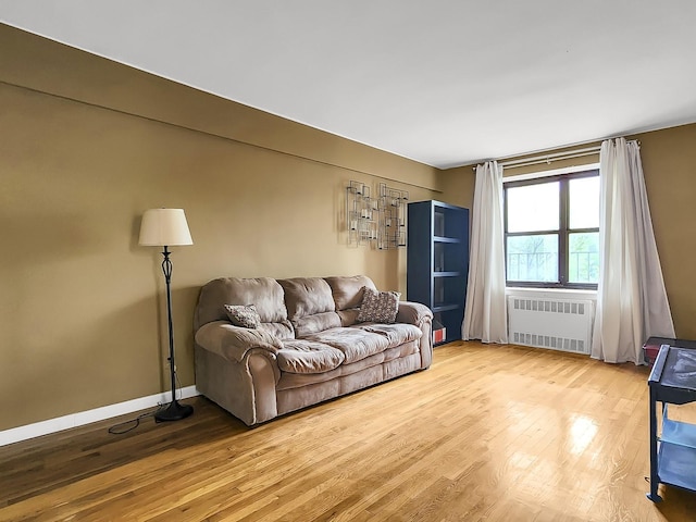 living area with radiator, wood finished floors, and baseboards