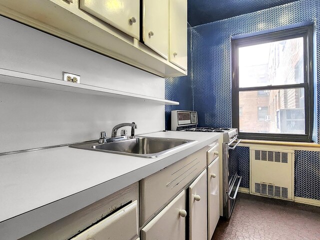 laundry room featuring radiator heating unit, healthy amount of natural light, and a sink